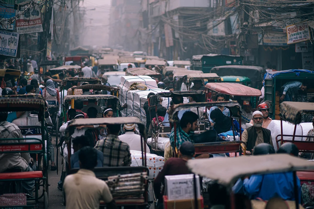 Dense, gridlocked traffic in Old Delhi, cycle-rickshaws and crowds filling the street.