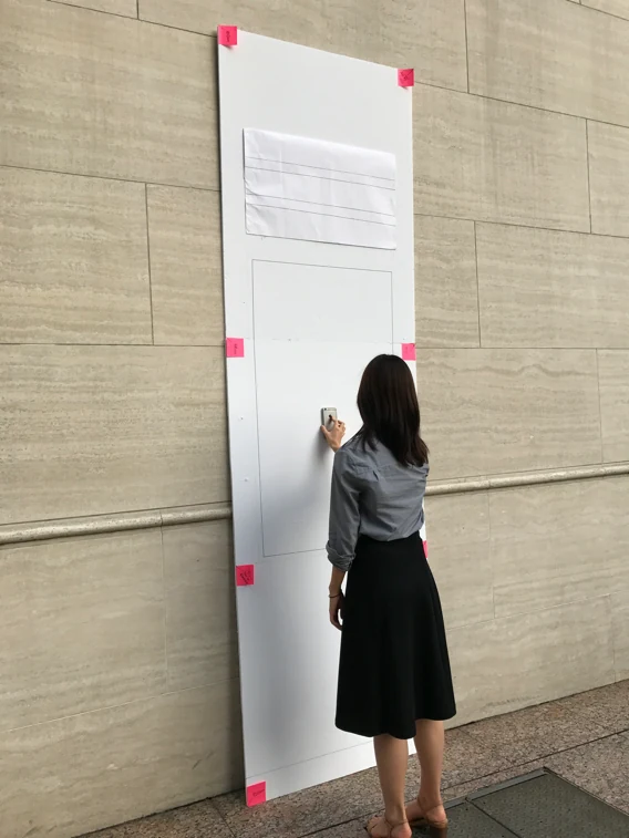 A full-scale foamboard mockup of the kiosk taped to a wall, tested at real size.